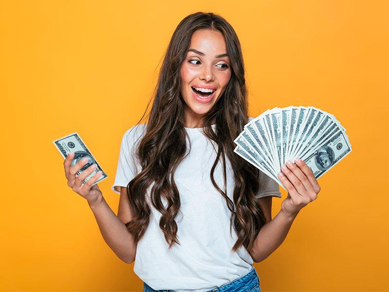 Imagem de uma mulher segurando cédulas de dinheiro e sorrindo ao descobrir que o preço do lifting não é tabelado