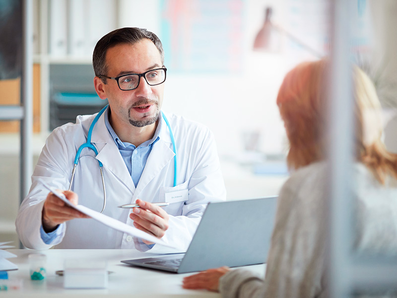 Médico entregando um papel com todas as recomendações para o pré-operatório da cirurgia que tira gordura dos flancos