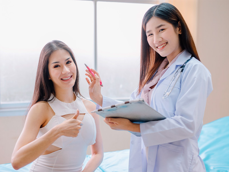 Paciente fazendo jóia e sorrindo junto com médica, pois tirar pontos não dói