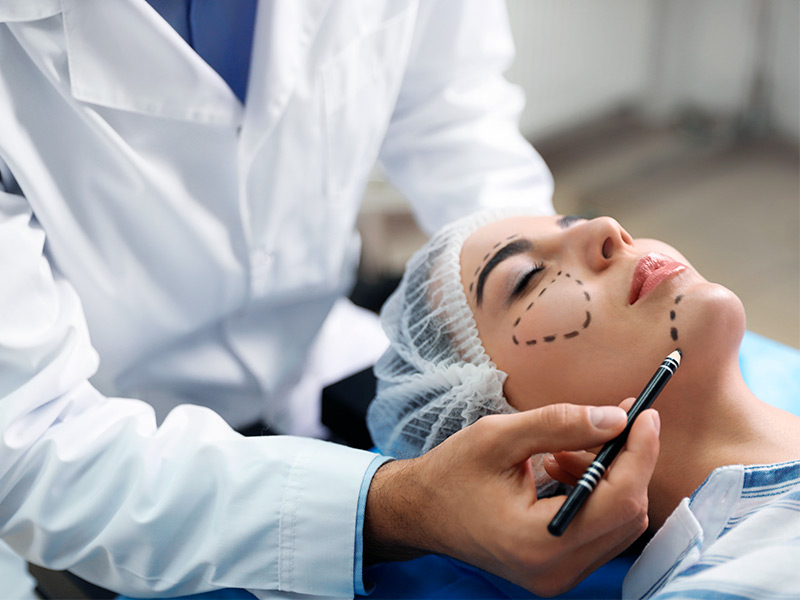 Médico fazendo as marcações no rosto de paciente para vários tipos de preenchimento