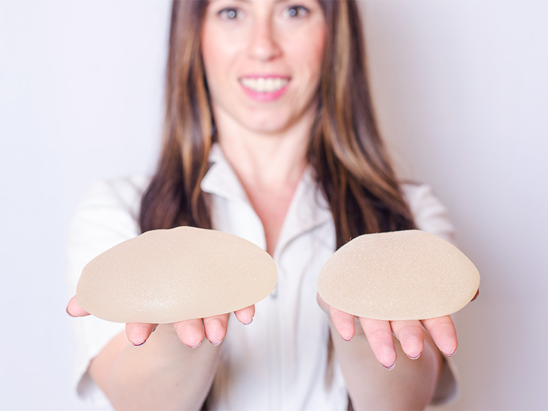 mulher mostrando dois tamanhos diferentes de prótese de silicone
