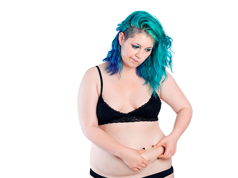 mulher apertando a barriga pensando na abdominoplastia