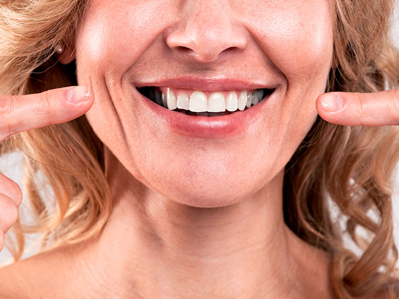 Mulher sorrindo e apontando para o rosto para mostrar o que é bigode chinês