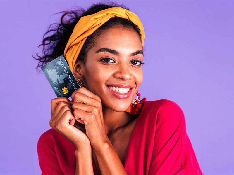 Mulher segurando um cartão de crédito perto do rosto feliz com o valor do preenchimento na boca