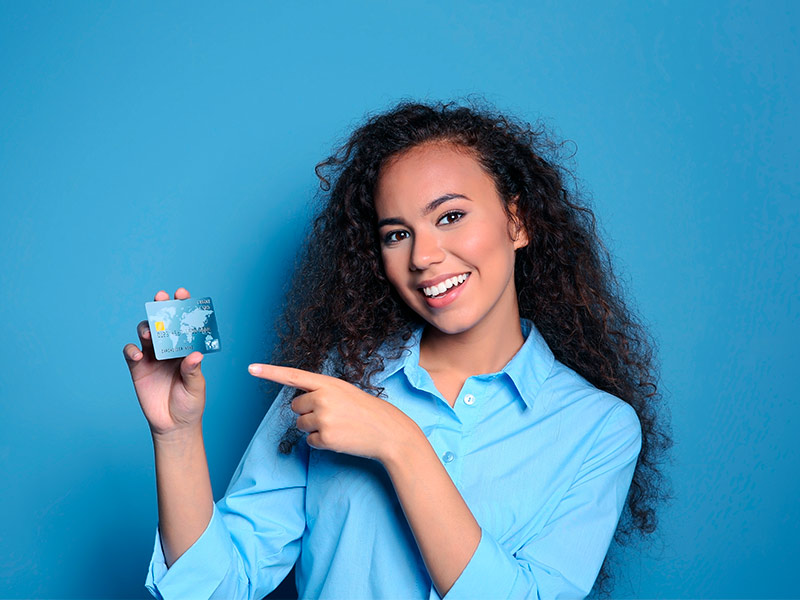 Mulher sorrindo apontando para um cartão de crédito feliz com o valor do procedimento nas melhores clínicas de São Paulo