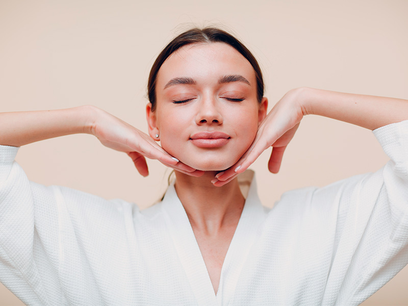 Imagem de uma mulher usando roupão enquanto ela planeja uma harmonização facial caseira