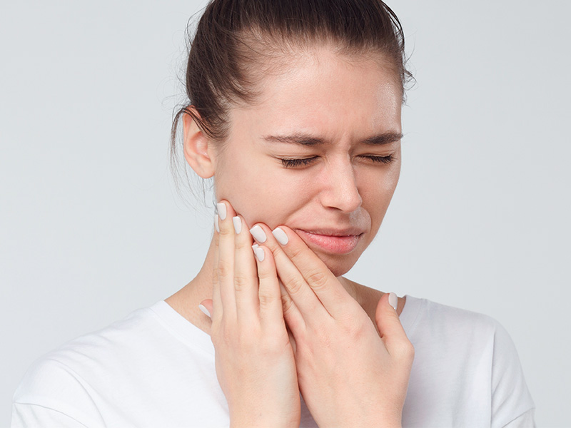 Imagem de uma mulher sentindo dores no rosto, uma das complicações da harmonização facial