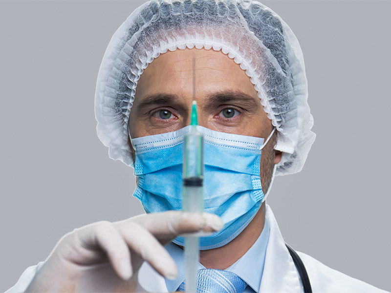 Imagem de um médico segurando uma seringa com substância preenchedora