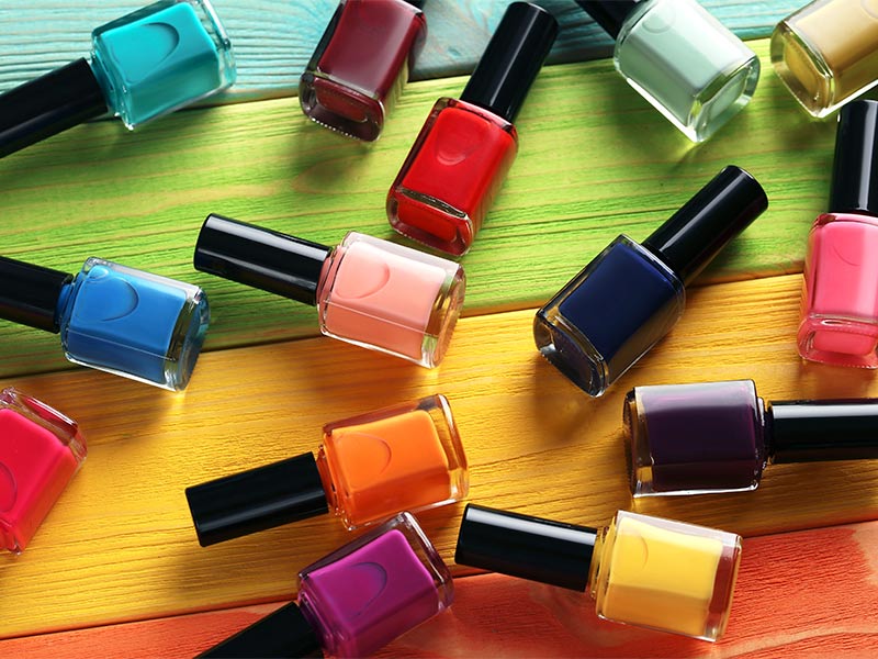 Imagem com esmaltes de diversas cores espalhados em uma mesa 