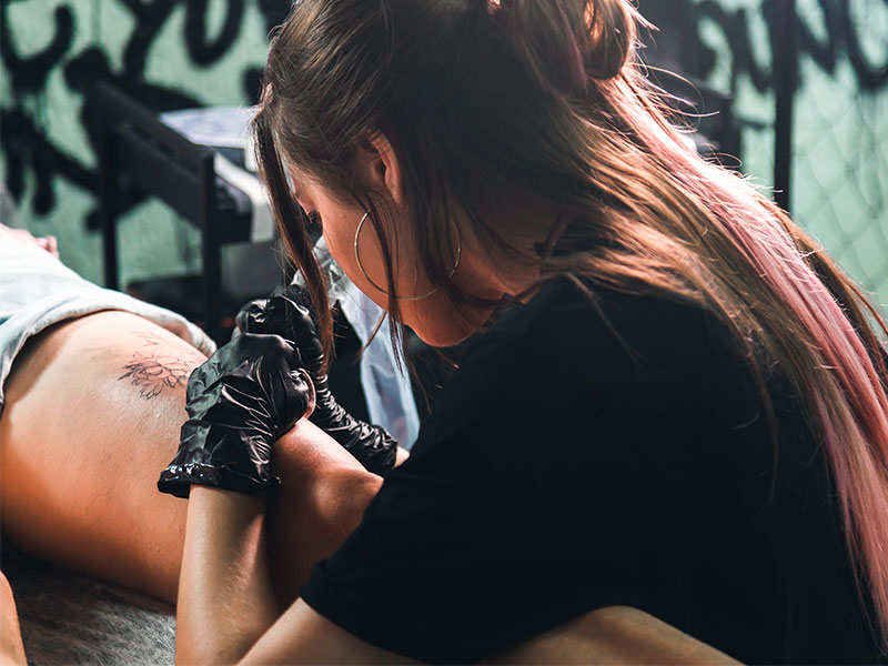 mulher fazendo tatuagem para cobrir estrias na coxa