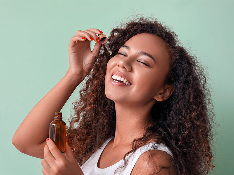 Imagem de uma mulher aplicando óleo essencial no rosto