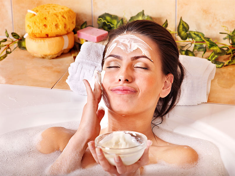 Imagem de uma mulher tomando banho na banheira e usando um creme caseiro para rosto