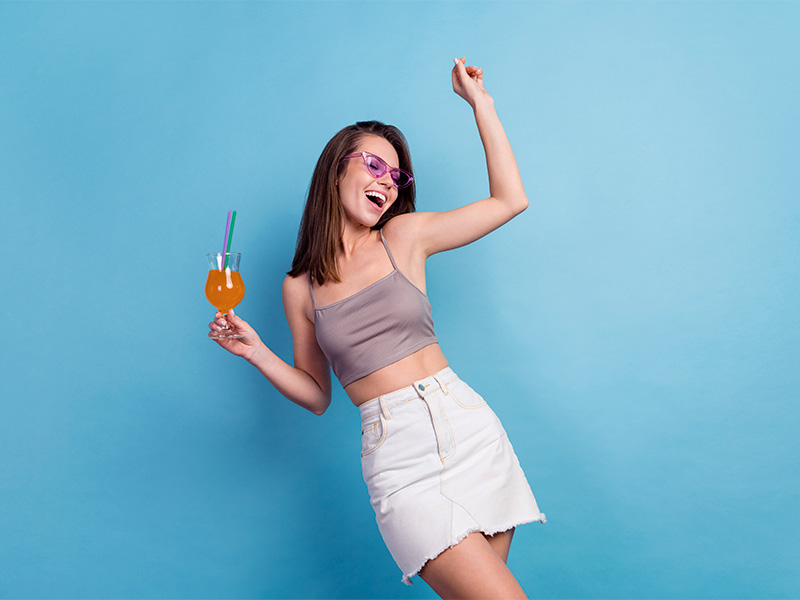 Mulher feliz dançando com uma taça de suco