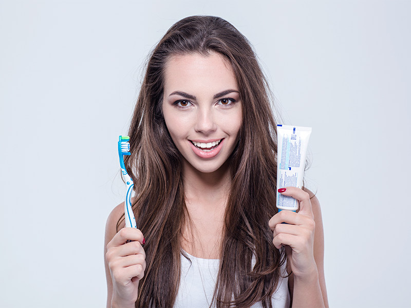 Mulher segurando uma pasta de dente e escova, se preparando para levantar a mama com pasta de dente