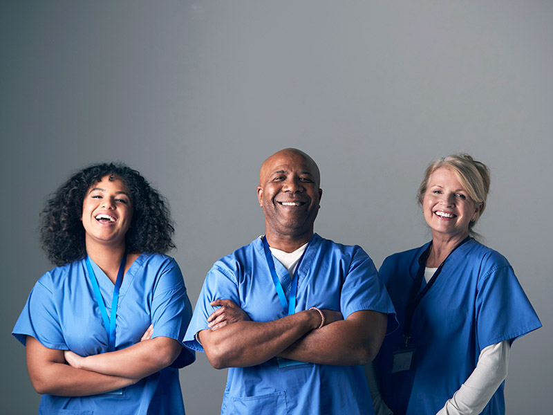 Três médicos de uniforme azul sorrindo