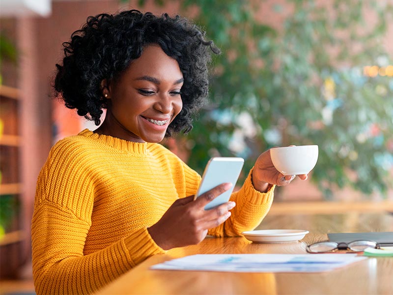 Veja resultados de outras pacientes! mulher tomado café e pesquisando qual o melhor cirurgião do mundo no celular