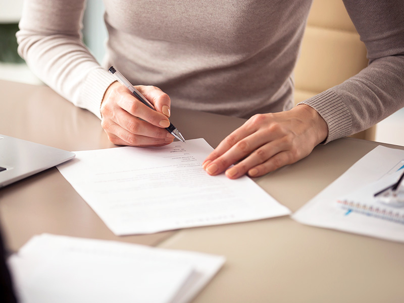 Imagem de uma mulher assinando um contrato e analisando o que está incluso no valor da lipoescultura