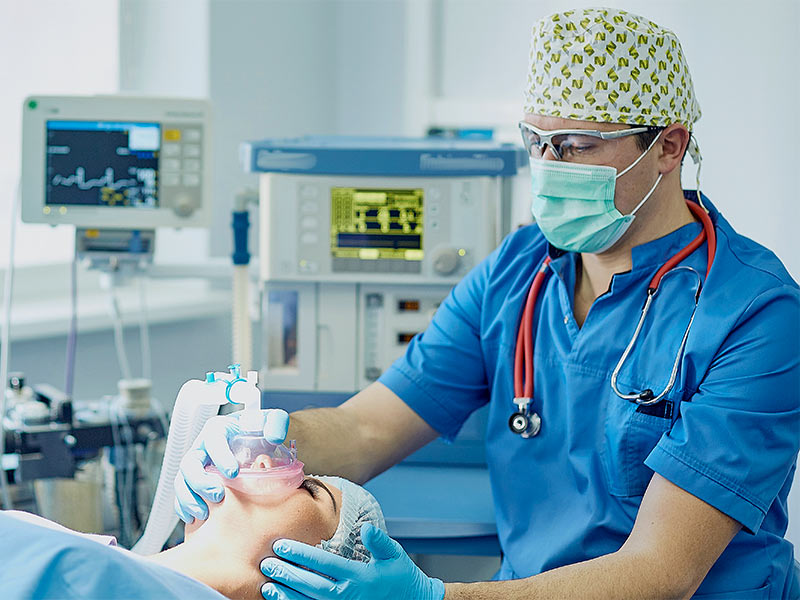 médico manuseando a anestesia geral em uma paciente
