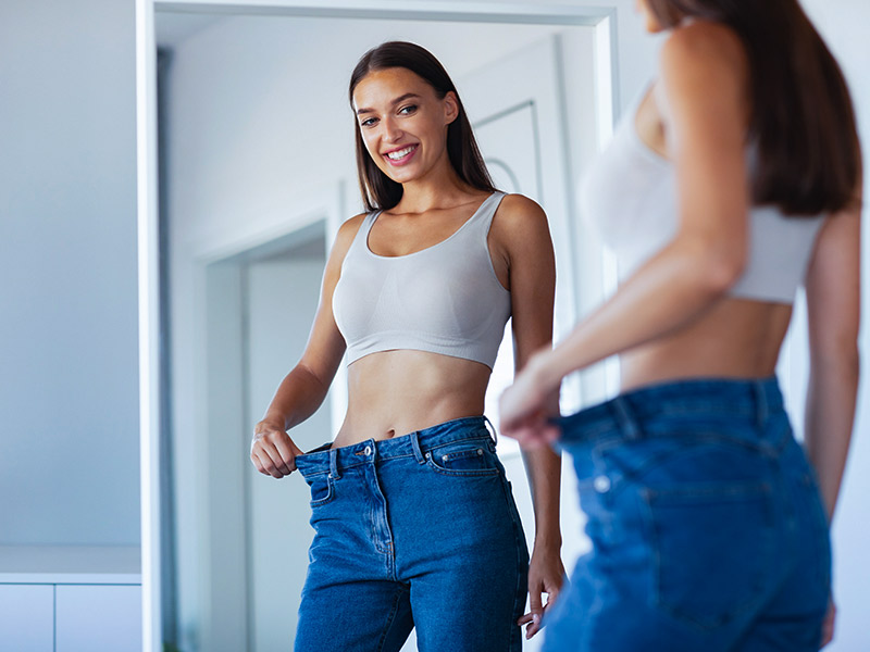 Os cuidados durante os 20 dias depois da abdominoplastia mulher se olhando no espelho depois de 20 dias de abdominoplastia