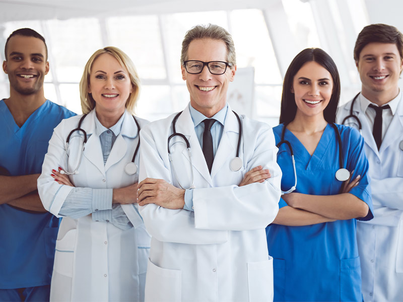 Imagem de uma Equipe Médica multidisciplinar formada por duas profissionais mulheres e três homens