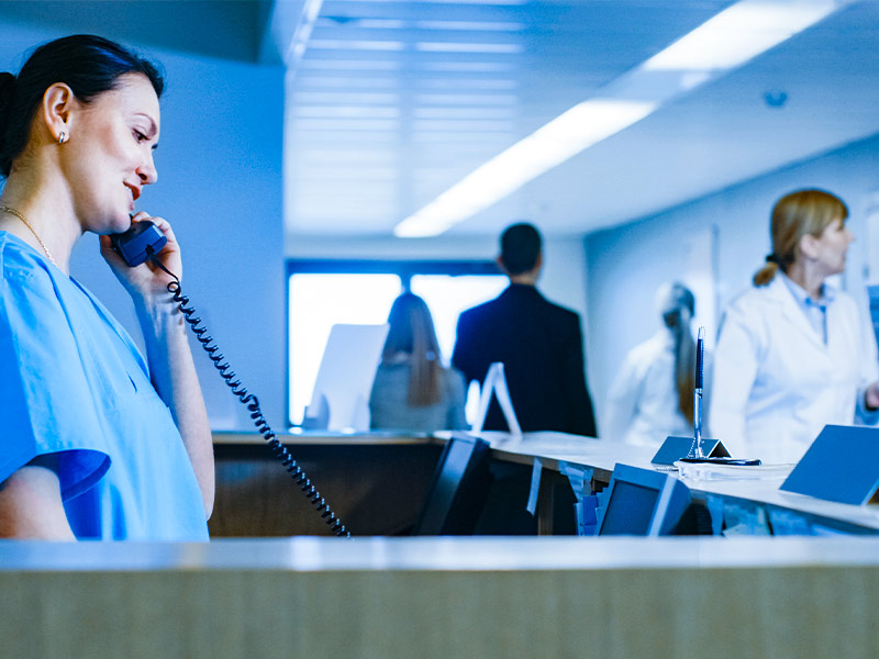 mulher trabalhando em hospital falando no saguão por telefone