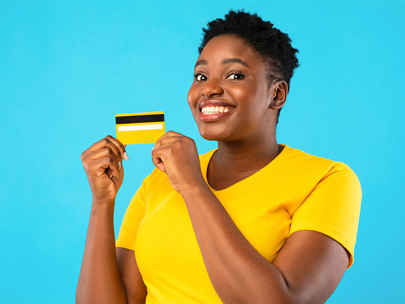 Imagem de uma mulher segurando um cartão de crédito e expressão de felicidade