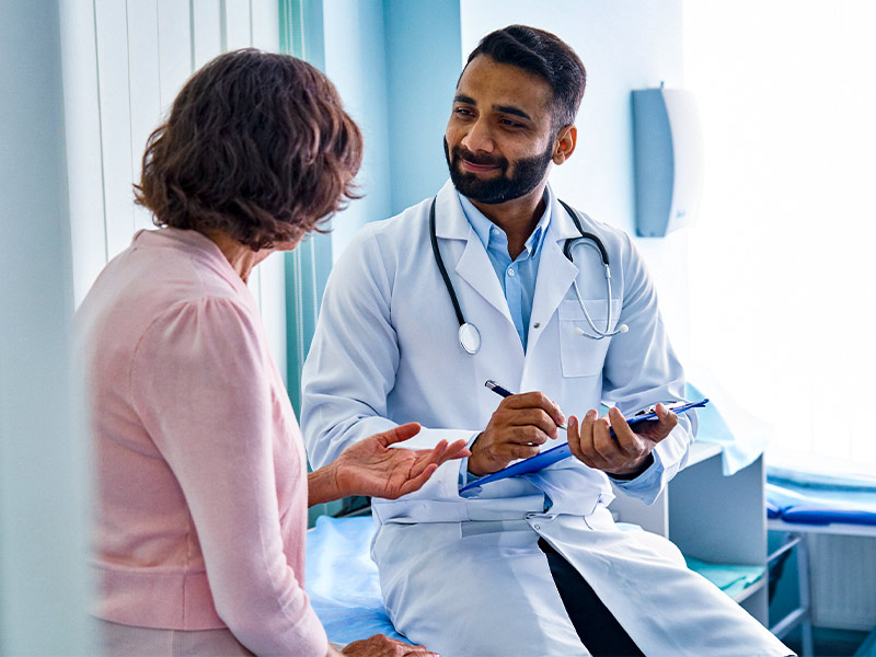 Médico segurando uma prancheta na mão e fazendo a APA com paciente