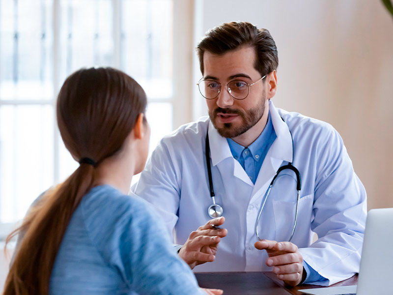 Imagem de um cirurgião plástico conversando com a paciente após a cirurgia no hospital