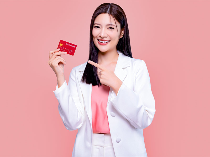 Mulher feliz segurando cartão de crédito depois de pagar o silicone
