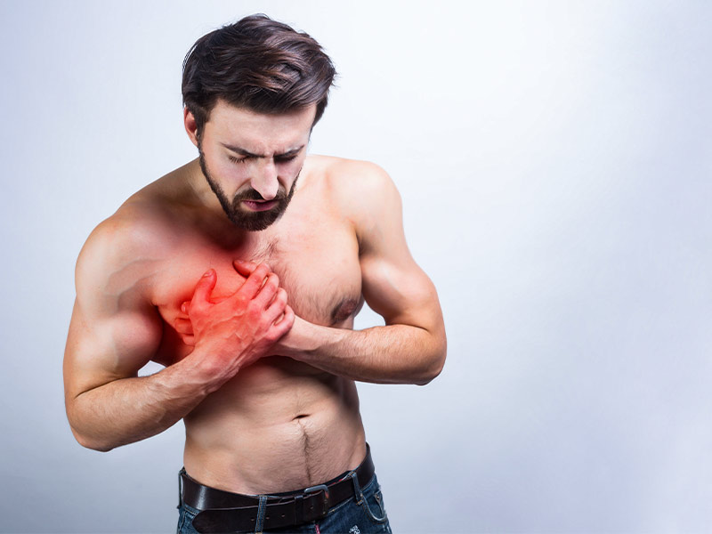 Homem sem camisa, apertando o peito direito, com dor