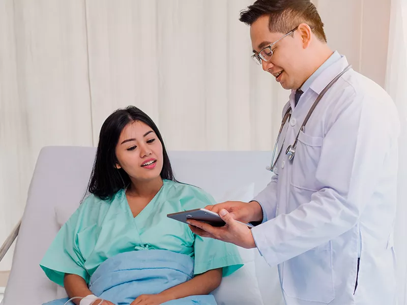 Quando o Sequel é usado na cirurgia? Médico explicando para paciente na maca como evitar êmbolos após cirurgia com a bota para trombose sequel