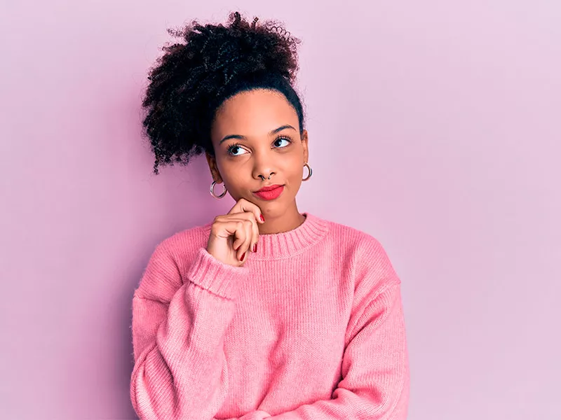 Saiba para que serve o ácido hialurônico Imagem com fundo rosa e uma mulher com expressão pensativa, se perguntando para que serve ácido hialurônico
