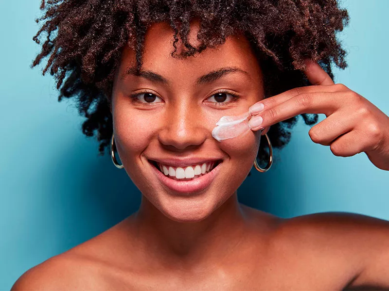 Você sabe qual é o melhor creme com AH? Imagem de uma mulher passando creme com ácido hialurônico no rosto