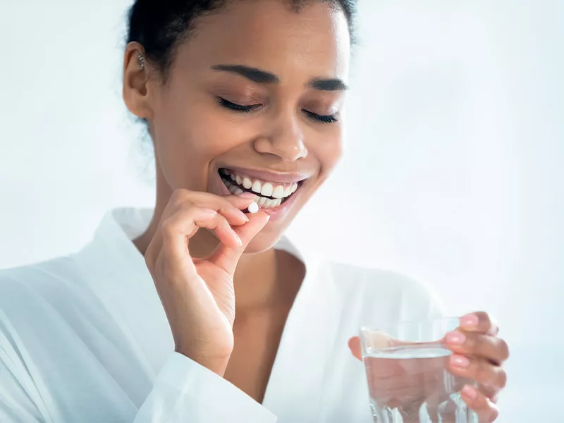 Você já conhece o colágeno verisol? Imagem de mulher tomando uma cápsula de colágeno Verisol com ácido hialurônico