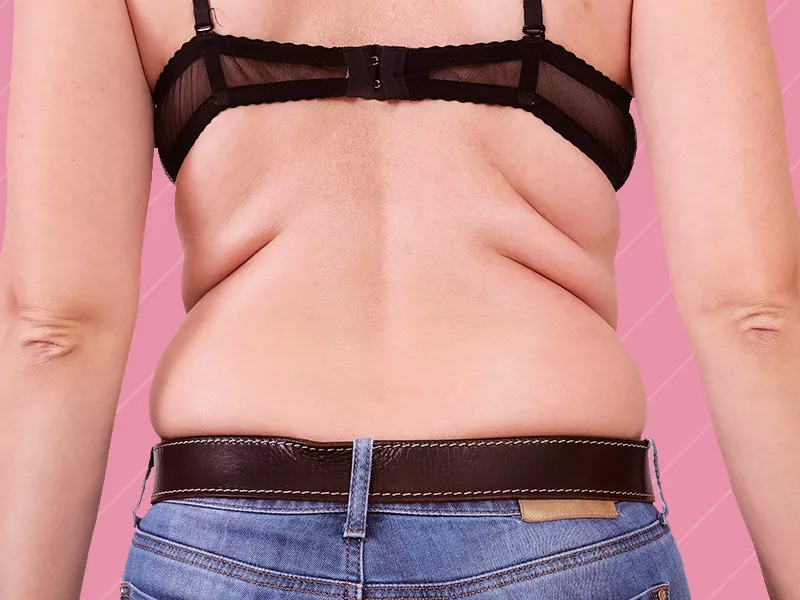 O que é lipo nas costas? imagem de uma mulher de costas em um fundo rosa, ela possui gordurinhas que podem ser removidas com a lipoaspiração nas costas