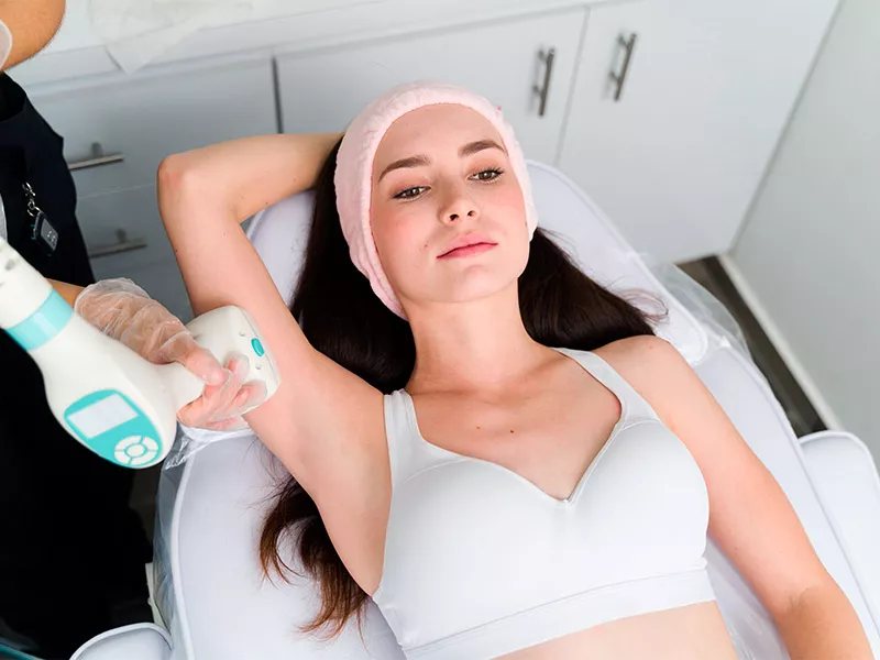 Tratamentos estéticos e o uso de sutiãs modeladores funcionam? Paciente de faixa rosa no cabelo fazendo sessão de radiofrequência para seios caídos