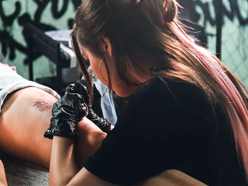COMO É FEITA A CAMUFLAGEM DE ESTRIAS NA BARRIGA? mulher fazendo tatuagem para cobrir estrias na coxa