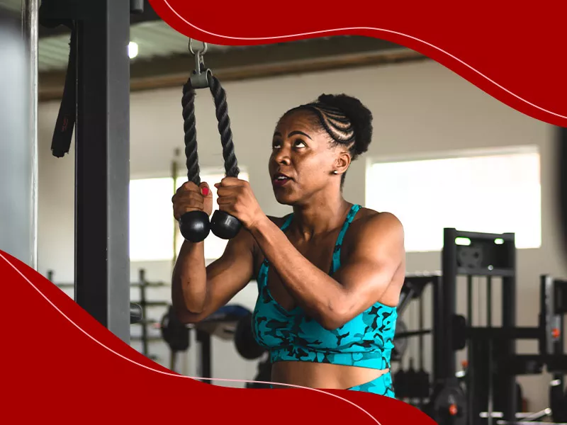 Mulher de top azul na academia, fazendo exercícios para os braços.